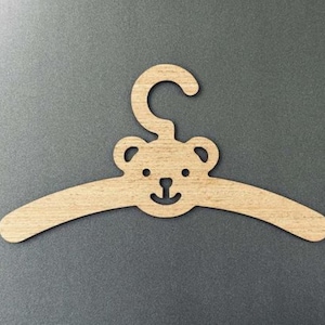 Pu&ograve; includere: Un attaccapanni in legno a forma di orso. L'attaccapanni marrone chiaro ha un design curvo e un gancio. La faccia dell'orso &egrave; ritagliata con due orecchie, occhi e una bocca sorridente.