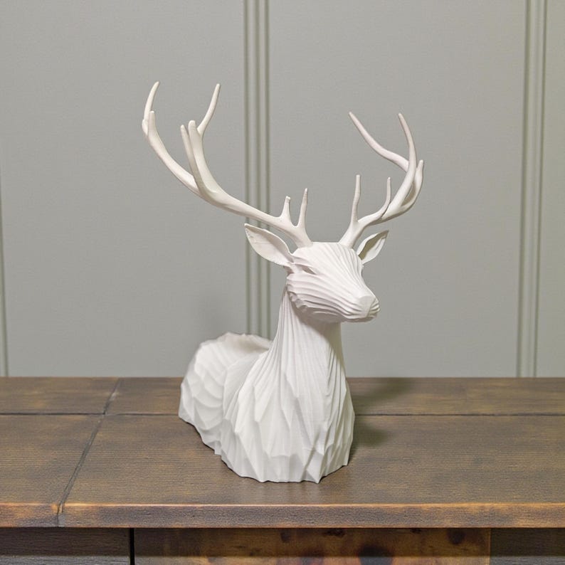 Puede incluir: Escultura de ciervo blanca con textura tallada detallada. El ciervo tiene grandes astas y est&aacute; en posici&oacute;n de descanso. La escultura es de material s&oacute;lido y est&aacute; sobre una superficie de madera. Ideal para decoraci&oacute;n del hogar.