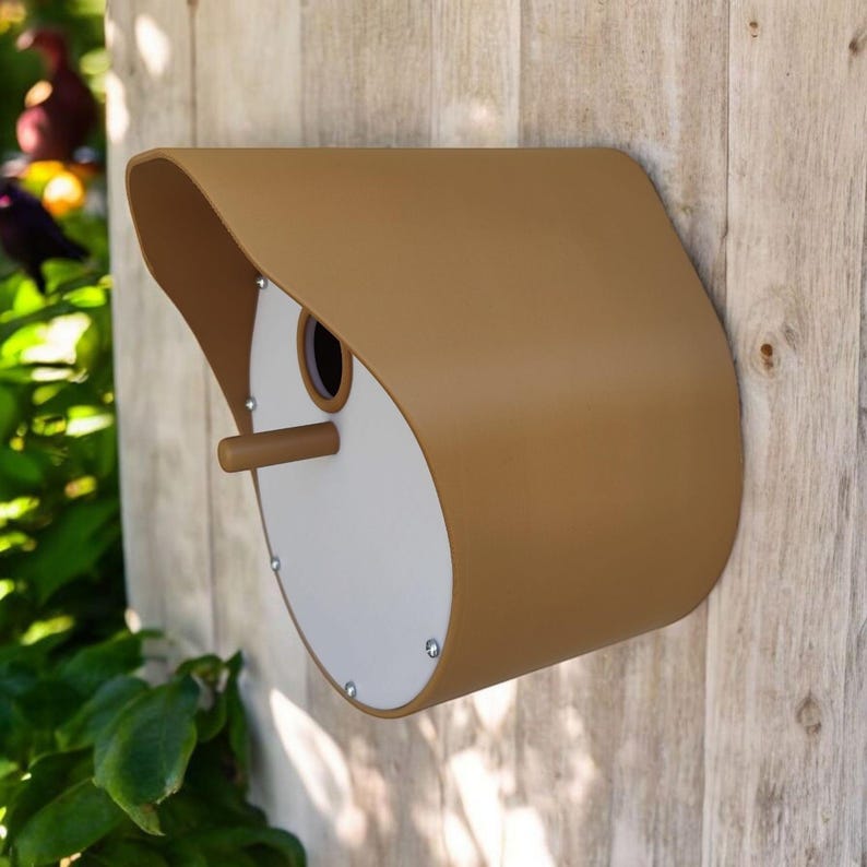 May include: A brown and white birdhouse with a rounded, curved roof and a small opening for birds to enter. The birdhouse is mounted on a wooden wall.