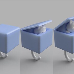 May include: A light blue cube-shaped hook with a white cat figurine inside. The cube has a hinged lid and a curved white hook. The cat figurine is white and has a smiling face.