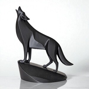 May include: A black geometric sculpture of a howling wolf. The wolf is standing on a dark, angled base. The sculpture has a modern, angular design and is set against a white background.