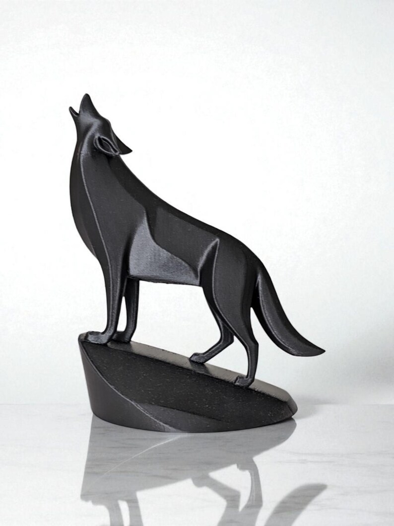 May include: A black geometric sculpture of a howling wolf. The wolf is standing on a dark, angled base. The sculpture has a modern, angular design and is set against a white background.