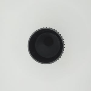 May include: A top-down view of a black cylindrical object with a textured, ridged exterior. The interior is a smooth, dark void. The object is set against a plain white background.