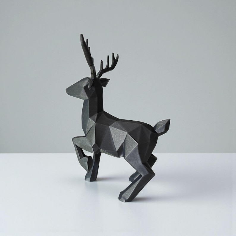May include: A black geometric deer sculpture with a modern, angular design. The sculpture is posed mid-stride, with its legs in motion. The antlers are detailed, and the overall aesthetic is minimalist and contemporary. The deer is made of a solid material.