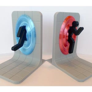 May include: A pair of gray bookends featuring a portal design. One bookend has a blue portal with a black figure, the other has a red portal with a black figure. The bookends have a curved base and a tiled pattern.