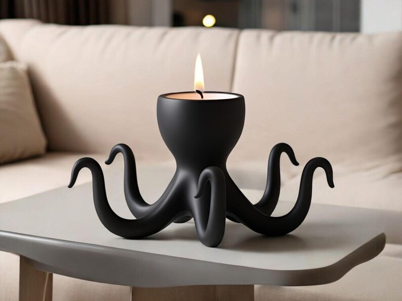May include: A black octopus-shaped candle holder with a lit candle. The candle holder has eight curved tentacles and a central cup to hold the candle. The design is modern and sculptural, suitable for home decor.
