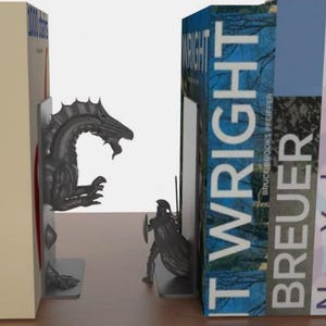 May include: A pair of decorative bookends featuring a dragon and a knight. The dragon bookend is a dark gray color and the knight is also dark gray. The bookends are holding up books with the word "WRIGHT" visible.