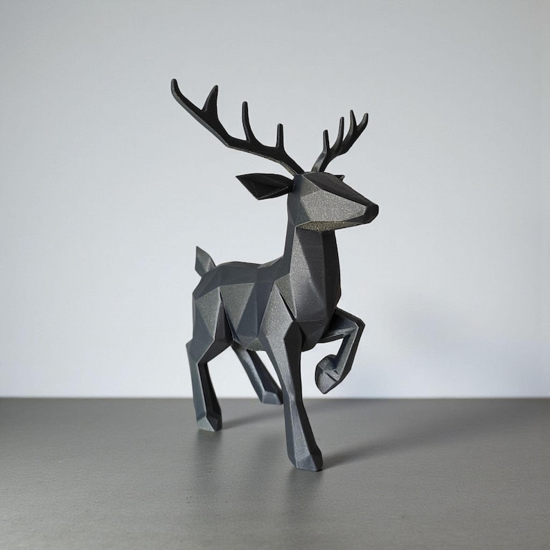 May include: A geometric, black deer sculpture with a modern design. The deer is depicted in a running pose, with its antlers prominently displayed. The sculpture is made of a matte material and sits on a gray surface.