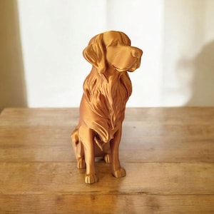 May include: A golden-colored dog statue, likely a Golden Retriever, sits on a wooden surface. The sculpture has detailed fur and a focused gaze, showcasing the breed's characteristics. The statue is a decorative item.