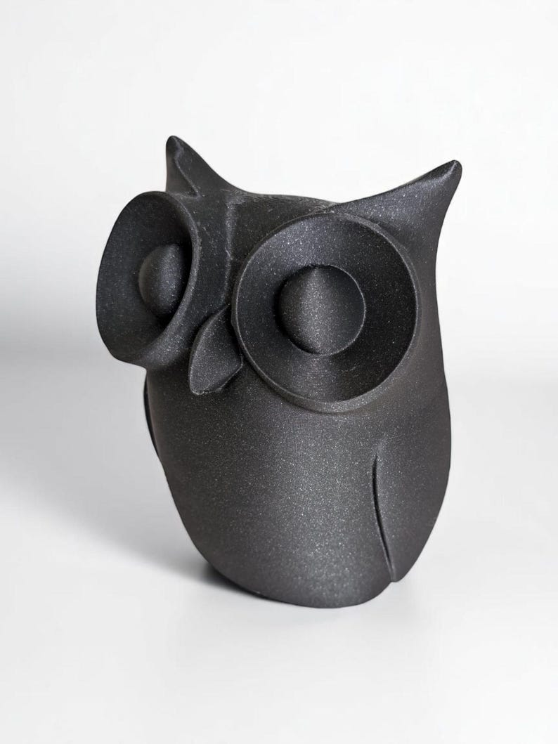 Op de afbeelding: Een matzwarte uilfiguur met grote, ronde ogen en puntige oorpluimen. De uil is een decoratief item, waarschijnlijk voor interieurdecoratie, tegen een effen witte achtergrond.