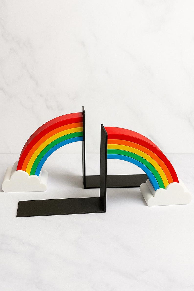 Puede incluir: Soportes para libros con forma de arco&iacute;ris. Cada uno presenta un dise&ntilde;o de arco&iacute;ris con arcos rojos, naranjas, amarillos, verdes, azules e &iacute;ndigo. El arco&iacute;ris se asienta sobre una base de nube blanca, con un soporte rectangular negro.