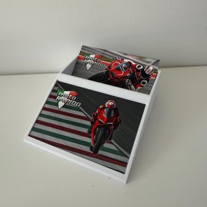May include: White display box with images of a red motorcycle racing on a track. The box has the words "moto RAPIDO" in green, white, and red. The images show a motorcycle racer in red gear.