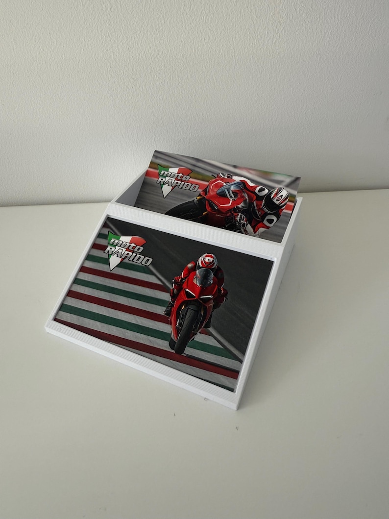 May include: White display box with images of a red motorcycle racing on a track. The box has the words "moto RAPIDO" in green, white, and red. The images show a motorcycle racer in red gear.