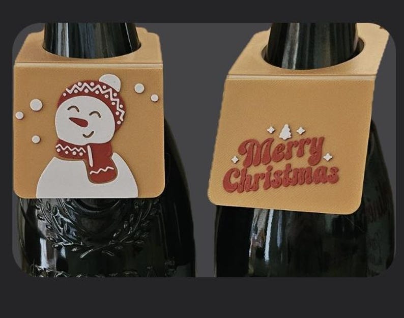 May include: Two Christmas-themed wine bottle tags. One tag features a snowman with a red scarf and hat, and the other says "Merry Christmas" in red lettering. Both tags are tan with a hole for the bottle neck.