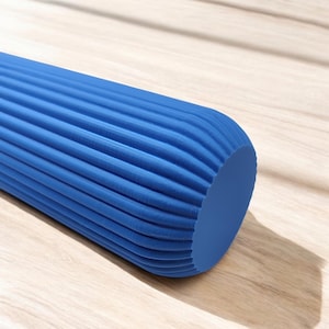 May include: A blue foam roller with a ridged surface. The cylindrical fitness tool is designed for muscle recovery and self-massage. The roller is made of a dense foam material and is shown on a light wood surface.
