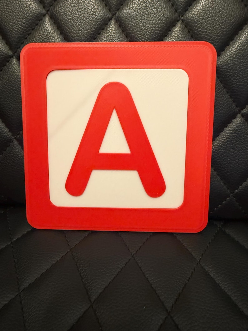 May include: A red and white square block featuring the letter "A". The letter "A" is in a bold, sans-serif font and is centered on a white background. The block has a red border, and the overall design is simple and clean. This block is likely used for educational purposes.