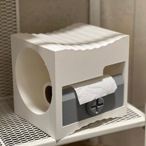 May include: A white, modern toilet paper holder with a wavy top edge. The holder has a gray pull-out section for dispensing paper and a circular opening for the roll. It sits on a white wire shelf.