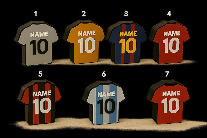 K&ouml;nnte beinhalten: Eine Sammlung von sieben Miniatur-Fu&szlig;balltrikots in verschiedenen Farben, jeweils mit der Nummer "10" und dem Wort "NAME" auf der R&uuml;ckseite. Die Trikots sind grau, gold, blau, rot, schwarz und hellblau.