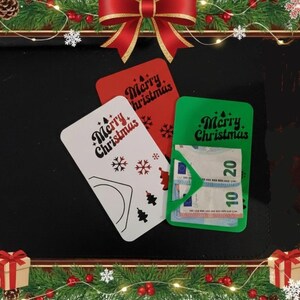 May include: Three Christmas gift card holders in red, white, and green. The white card has snowflakes and tree designs. The green card holds Euro banknotes. Each card has the text "Merry Christmas".