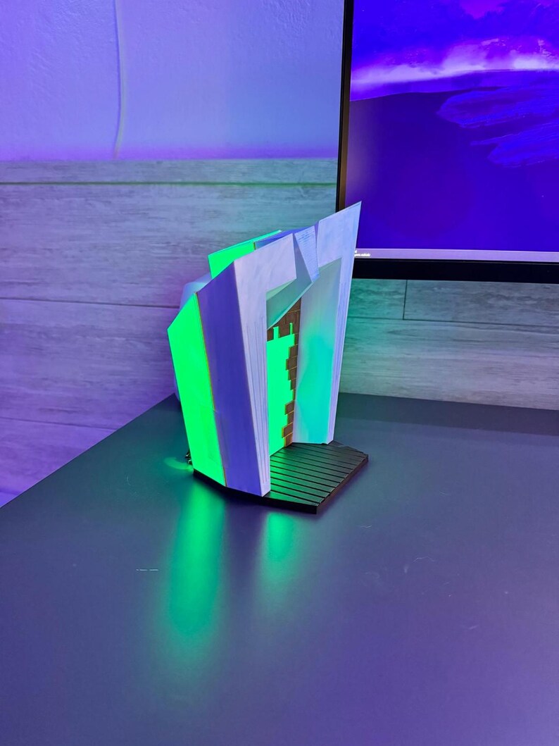 May include: A modern, abstract bookend design. The bookend features a geometric shape with white, green, and blue accents. The base is black, and the overall design is illuminated with green light, creating a futuristic aesthetic.
