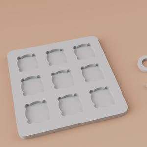 K&ouml;nnte beinhalten: Ein hellgraues Tic-Tac-Toe-Spielset. Das Set enth&auml;lt ein quadratisches Spielbrett mit neun Vertiefungen und zwei Spielsteinen: ein "O" und ein "X". Die Spielsteine und das Brett bestehen aus einem hellgrauen Material.