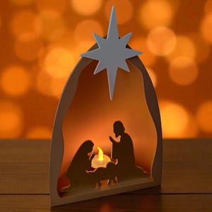 May include: A wooden nativity scene featuring a white star. The scene shows the silhouettes of Mary, Joseph, and baby Jesus, with a candle inside. The background is a warm orange colour.