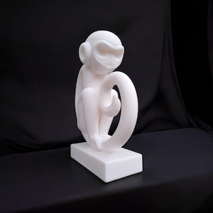 Puede incluir: Escultura blanca de un mono sentado con la cola enroscada. La escultura est&aacute; sobre una base rectangular. El acabado es liso y mate, sobre un fondo negro. Probablemente hecha de resina.