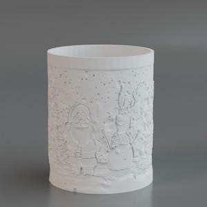May include: A white cylindrical candle holder with embossed Christmas-themed designs. The designs include Santa Claus and a snowman, set against a snowy background. The candle holder is made of a solid, opaque material.