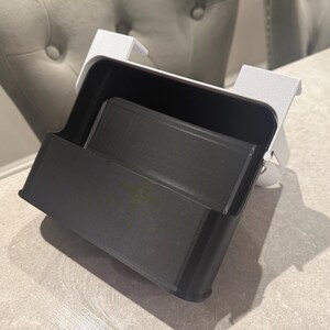 May include: A black and white desk organizer with a rectangular shape. The organizer has a tray and a holder. The organizer is made of plastic and is designed to hold office supplies. The organizer is sitting on a light-colored surface.