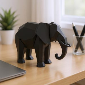 Op de afbeelding: Een zwarte geometrische olifant sculptuur met een slurf en grote oren. De olifant is gemaakt van een solide materiaal en wordt tentoongesteld op een houten oppervlak. De sculptuur is een decoratief item.
