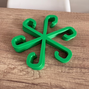 May include: A stack of bright green plastic hangers arranged in a starburst pattern. Each hanger has a curved hook shape. The hangers are on a wooden surface.