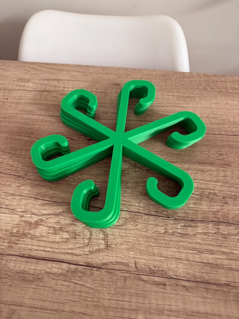 May include: A stack of bright green plastic hangers arranged in a starburst pattern. Each hanger has a curved hook shape. The hangers are on a wooden surface.