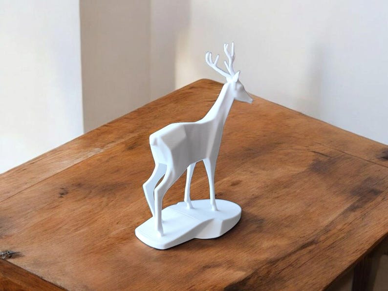 Puede incluir: Una escultura de ciervo geom&eacute;trico blanco con cuernos, de pie sobre una base blanca. El ciervo est&aacute; colocado sobre una superficie de madera, mostrando un dise&ntilde;o moderno y minimalista. Esta pieza decorativa a&ntilde;ade un toque de arte inspirado en la naturaleza.
