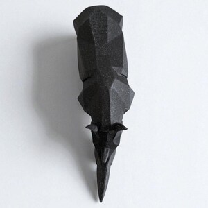 May include: A black, geometric rhino head sculpture. The rhino head is made of a matte black material and features a faceted design. The sculpture is displayed against a white background.