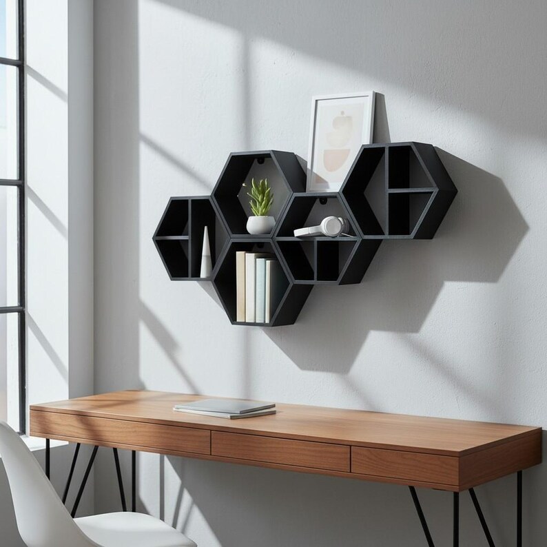May include: Black hexagonal wall shelves with a small plant, books, and headphones. The shelves are mounted on a light grey wall above a wooden desk with a laptop. The desk is made of wood.