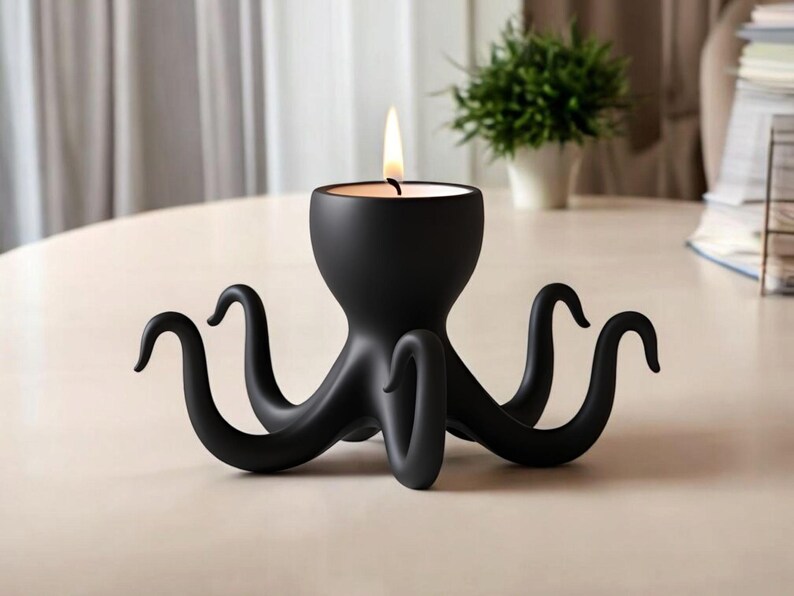 May include: A black octopus-shaped candle holder with a lit candle. The candle holder has eight curved tentacles and a round base. The candle flame is yellow and orange. The holder is on a light-coloured surface.