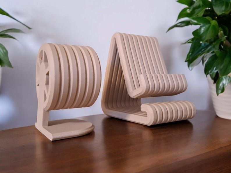 Puede incluir: Dos organizadores de escritorio de madera de color beige claro. Uno es un soporte para tel&eacute;fono con un dise&ntilde;o de listones, y el otro es un soporte redondo con un recorte en forma de estrella. Ambos son de madera.