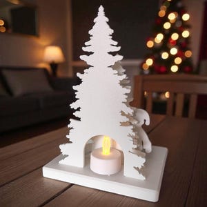 May include: A white, laser-cut Christmas tree-shaped candle holder with a small, round, battery-operated candle inside. The candle holder is on a wooden table, with a blurred Christmas tree in the background.