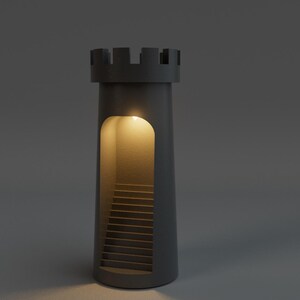May include: A dark gray, cylindrical decorative lamp shaped like a castle tower. The tower has a rectangular opening revealing a staircase illuminated by a warm light. The top of the tower has a crenelated design.