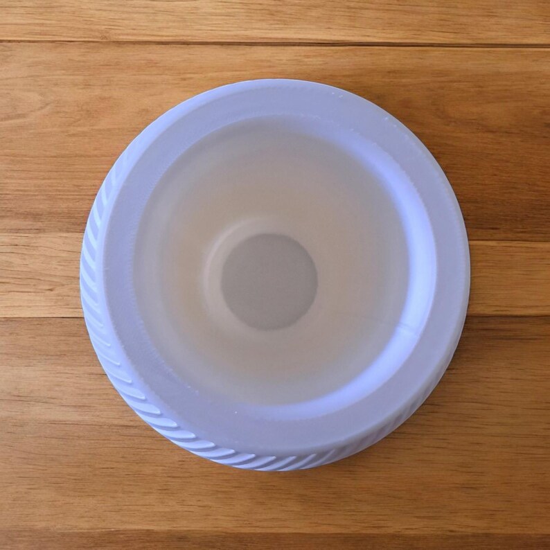 Puede incluir: Vista superior de un plato de pl&aacute;stico azul claro con borde estriado. El plato tiene una hendidura circular en el centro. Colocado sobre una superficie de madera.