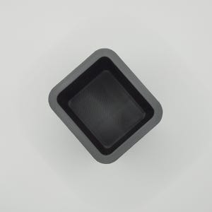 May include: A dark gray, square-shaped container with a slightly textured interior. The container has a raised, angled rim and a flat bottom. The object is set against a plain white background.