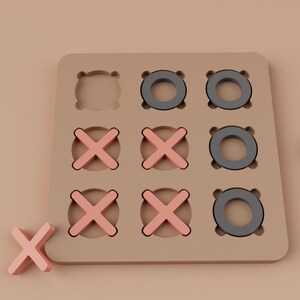 K&ouml;nnte beinhalten: Ein beiges Tic-Tac-Toe-Spiel aus Holz mit rosa X'en und grauen O's. Ein X und ein O sind getrennt von der Tafel. Das Spielbrett hat eine quadratische Form mit neun kreisf&ouml;rmigen Aussparungen f&uuml;r die O's und X's.