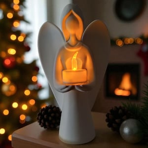 May include: A white angel figurine holding a glowing candle. The angel has outstretched wings and a serene expression. The candle emits a warm, inviting light, creating a cozy atmosphere. The background includes a Christmas tree with lights and a fireplace.