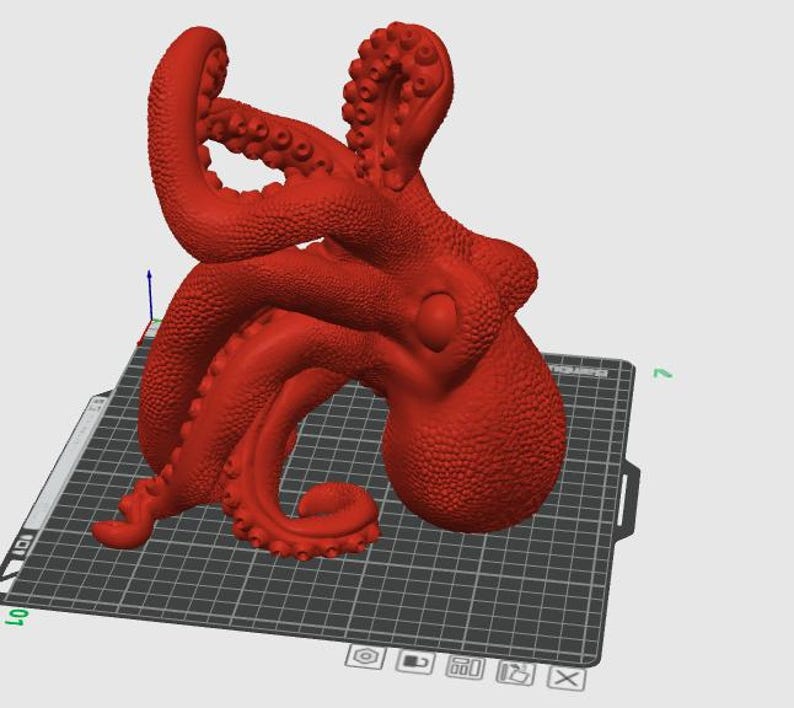 May include: A red octopus figurine with detailed tentacles and a textured surface. The octopus is positioned on a black and gray grid, likely a 3D printing bed. The figurine is a solid, three-dimensional object.