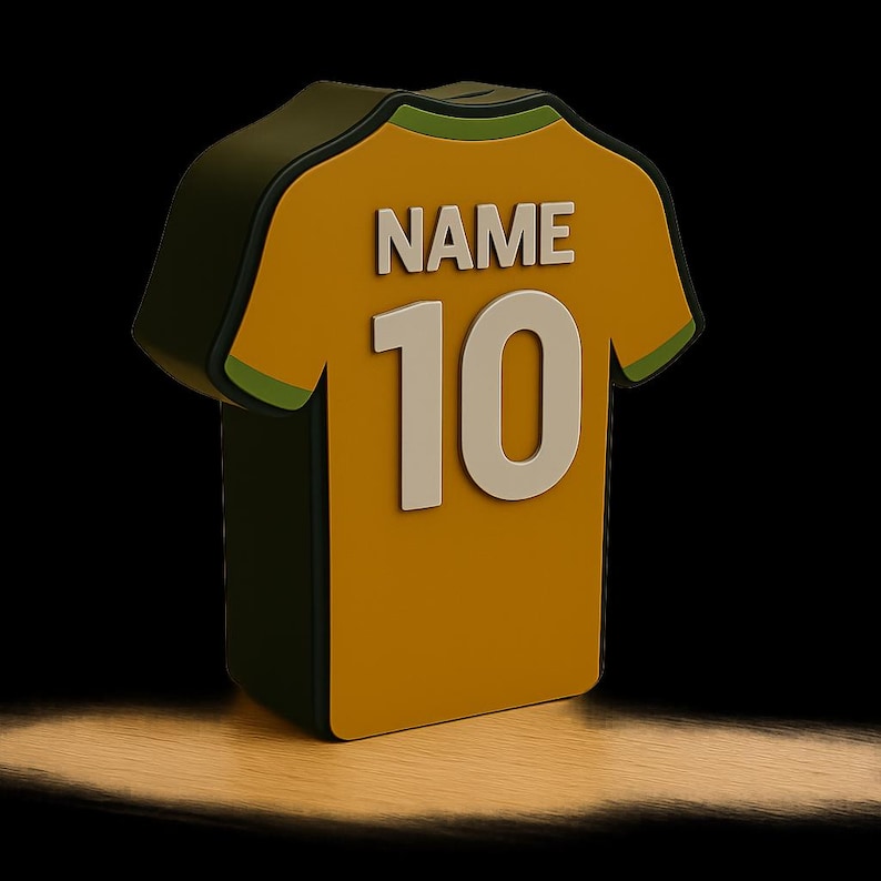 K&ouml;nnte beinhalten: 3D-Darstellung eines gelb-gr&uuml;nen Fu&szlig;balltrikots mit dem Wort "NAME" &uuml;ber der wei&szlig;en Nummer "10". Das Trikot hat eine dunkelgr&uuml;ne Kontur und ist vor einem schwarzen Hintergrund mit einem Spotlight-Effekt platziert.