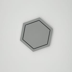 May include: A gray, geometric coaster with a black border. The coaster has a hexagonal shape and is set against a white background. The coaster is a solid color and has a simple, modern design.