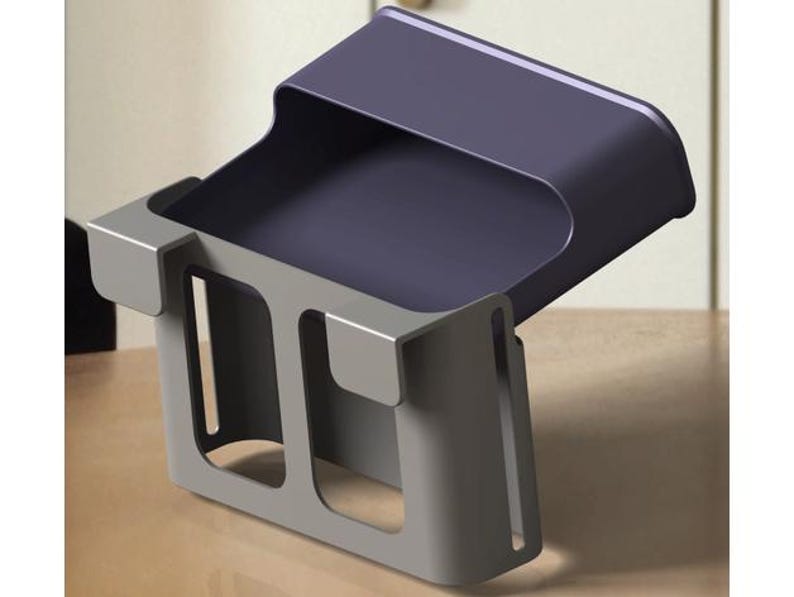 May include: A modern, two-tone desk organizer. The top section is a dark purple, while the base and sides are a light gray. The organizer has a tray-like top and a rectangular base with cut-out sections.
