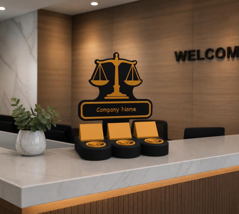 K&ouml;nnte beinhalten: Ein moderner Empfangstresen mit Marmorplatte und Holzakzenten. Der Tresen verf&uuml;gt &uuml;ber drei schwarze und goldene M&uuml;nzhalter und ein Schild mit einem Waage-Logo und dem Text "Company Name". Eine kleine Pflanze in einer wei&szlig;en Vase steht auf der Theke.