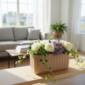 May include: A rectangular, light brown planter filled with white roses, purple hydrangeas, and green ivy. The planter sits on a wooden table in a well-lit room with a couch and window in the background.