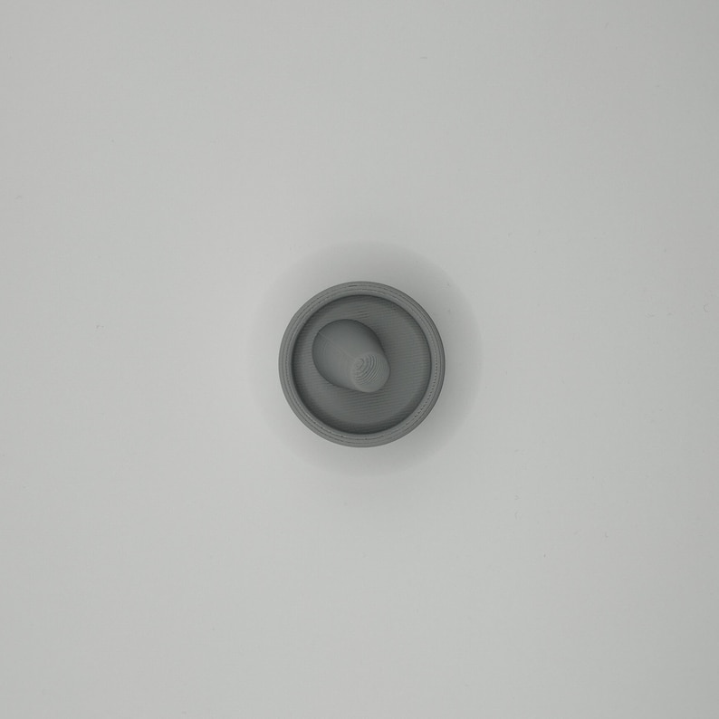 Pode incluir: Uma rolha cinzenta com um design circular e uma pega cil&iacute;ndrica saliente. A rolha &eacute; feita de um material s&oacute;lido e foi concebida para se encaixar na abertura de uma garrafa. O design &eacute; simples e funcional.